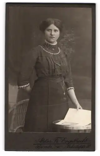 Fotografie Fr. Engelbrecht, Bünde i. W., Bahnhofstrasse 30, Junge Dame im Kleid mit Zeitung