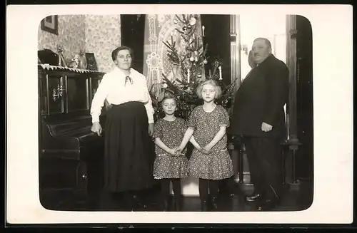 Fotografie Weihnachten, beleibtes Paar mit Töchtern vor Weihnachtsbaum