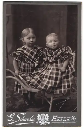 Fotografie G. Schwedes, Heide i. H., Bahnhofsgang 5, Kleines Mädchen und Kleinkind in karierten Kleidern