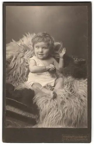 Fotografie W. Laskawy, Kiel, Holtenauerstrasse 32, Süsses Kleinkind im Hemd sitzt auf Fell