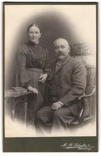 Fotografie M. B. Schultz, Flensburg, Älteres Paar in hübscher Kleidung