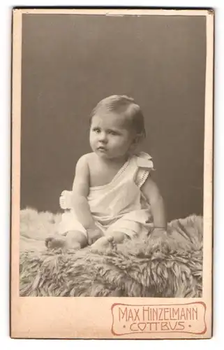 Fotografie Max Hinzelmann, Cottbus, Kleinkind im Hemd sitzt auf einem Fell