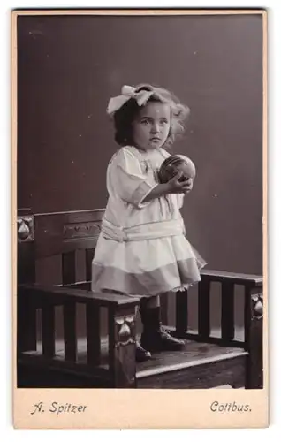 Fotografie A. Spitzer, Cottbus, Kleines Mädchen mit Schleife im Haar und Ball