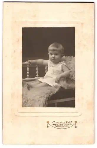Fotografie Samson & Co., Essen /Ruhr, Limbeckerstrasse 12, Kleines Kind im Hemd sitzt auf einem Fell