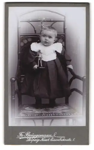 Fotografie Friedr. Brüggemann, Leipzig-Neustadt, Eisenbahnstrasse 1, Kleinkind im Kleid steht auf einem Stuhl