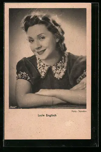 AK Schauspielerin Lucie Englisch lächelt freundlich mit überneinandergeschlagenen Armen