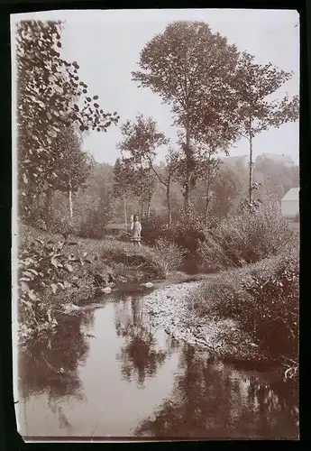 Fotografie Brück & Sohn Meissen, Ansicht Herzogswalde, kleines Mädchen mit Rechen steht am Fluss