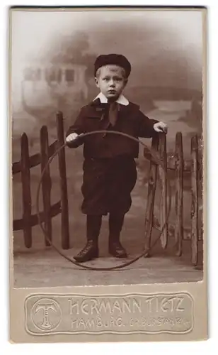 Fotografie Warenhaus Hermann Tietz, Hamburg, Gr. Burstah 12-14, Kleiner Junge im Anzug mit einem Reifen