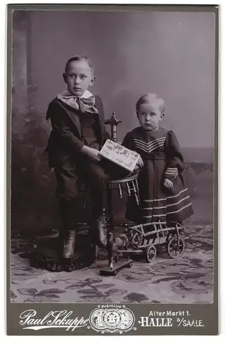 Fotografie Paul Schuppe, Halle a. Saale, Alter Markt 1, Kinderpaar in modischer Kleidung mit Bilderbuch