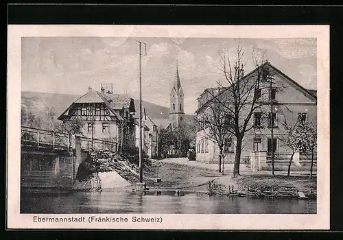 AK Ebermannstadt / Fränk. Schweiz, Häuserpartie am Ufer mit Blick auf die Kirche