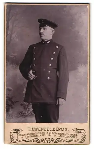 Fotografie Th. Wenzel, Berlin, Andreas Strasse Ecke Grüner Weg, Eisenbahner in Uniform mit Schirmmütze