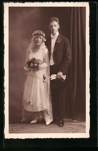 Foto-AK Glückliches junges Brautpaar, er mit Zylinder, sie mit langem Schleier und Blumenstrauss