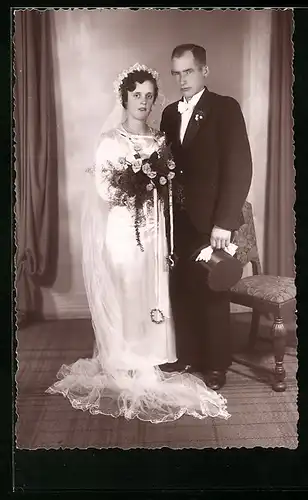 Foto-AK Glückliches junges Brautpaar, er mit Zylinder, sie mit Blumenstrauss