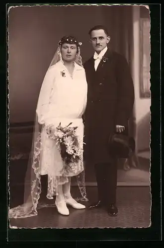 Foto-AK Junges Brautpaar im Fotostudio, sie mit Blumenstrauss, er mit Zylinder