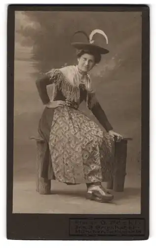 Fotografie O. Pöckl, München, Dachauerstr. 6, Dame mit Hut in Tracht auf Holzbank sitzend