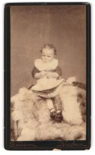 Fotografie Gillam, Brechin, Kind im Kleid sitzt auf Fell