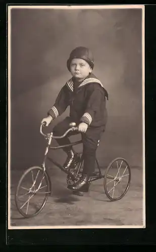 Foto-AK Knabe im Matrosenanzu mit Kappe auf seinem Dreirad