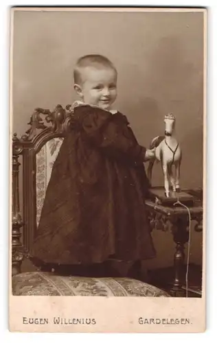 Fotografie Eugen Willenius, Gardelegen, Portrait lächelndes Mädchen mit Spielzeugpferd