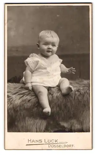 Fotografie Hans Luck, Düsseldorf, Bismarckstr. 65, Portrait süsses blondes Kleinkind auf einem Fell sitzend