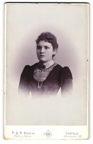 Fotografie P. & H. Koch, Crefeld, Rheinstr. 32, Portrait dunkelhaarige Schönheit in Bluse mit Brosche am Kragen