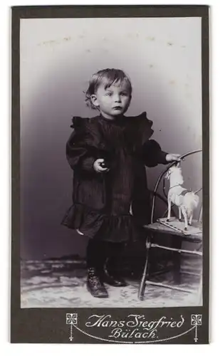 Fotografie Hans Siegfried, Bülach, Portrait niedliches Mädchen mit Spielzeugpferd