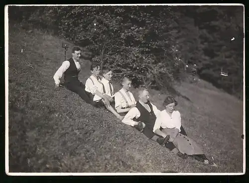 Fotografie Burschen und junge Frau in einer Reihe hintereinander sitzend