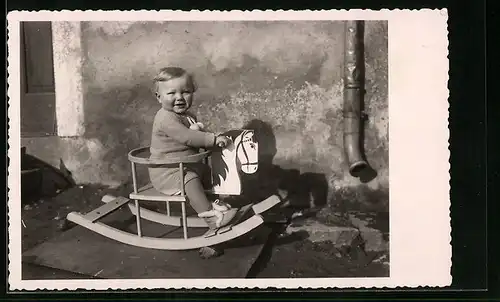 Foto-AK Niedliches Kleinkind auf einem Schaukelpferd