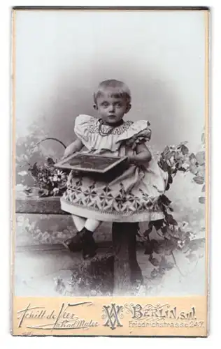 Fotografie Achill de Veer, Berlin, Friedrichstr. 247, Kind im Kleid mit einem Bild