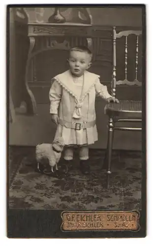 Fotografie G. F. Eichler, Schmölln /S.-A., Kleiner Junge im Kleid mit einem Spieltier