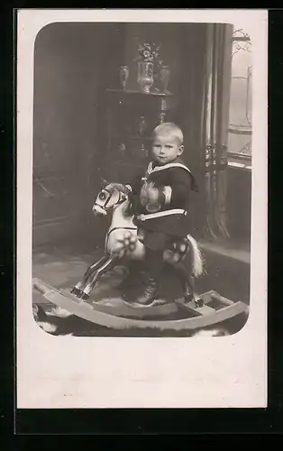 Foto-AK Kleiner Junge in Matrosenkleidung auf einem Schaukelpferd