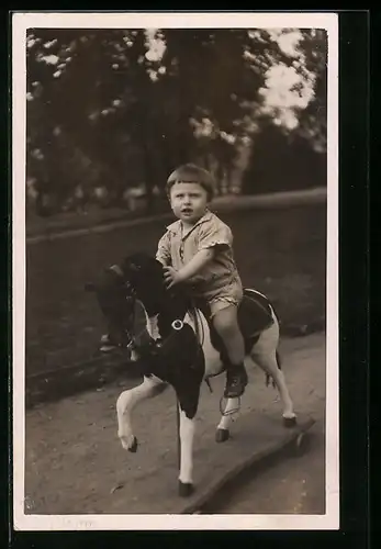 Foto-AK Kleiner Junge auf Spielzeugpferd in einem Park