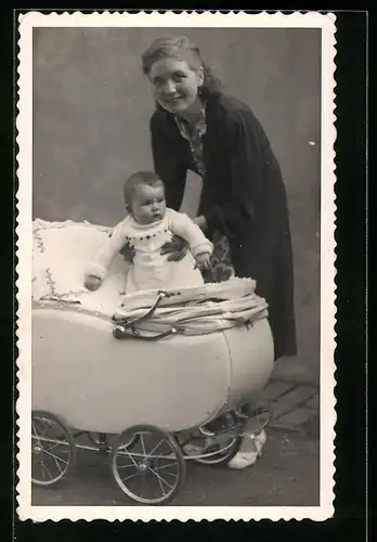 Foto-AK Mutter hebt Kleinkind in einen Kinderwagen