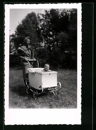 Foto-AK Junge Dame mit Kleinkind im Kinderwagen auf einer Wiese