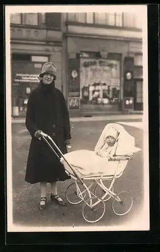 Foto-AK Junge Dame mit Kleinkind im Kinderwagen vor einem Geschäft