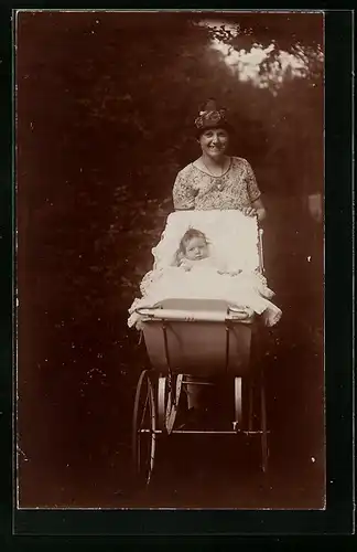 Foto-AK Lächelnde Mutter mit Kleinkind im Kinderwagen im Grünen