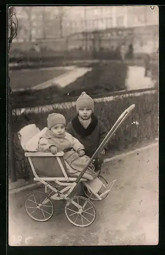 Foto-AK Knabe mit Kind im Kinderwagen vor einer Parkanlage