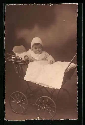 Foto-AK Lächelndes Kleinkind mit Mütze im Kinderwagen