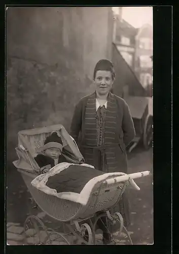 Foto-AK Junge Mutter mit Kleinkind im Kinderwagen vor einer Hauswand