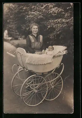 Foto-AK Glückliche junge Mutter mit Baby im Kinderwagen in einem Park