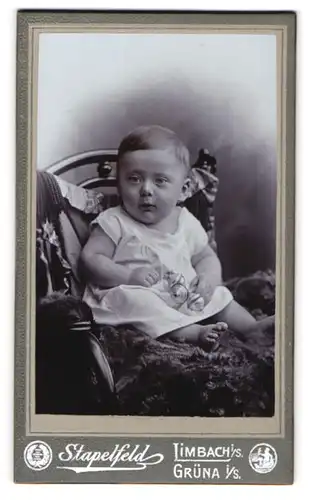 Fotografie Stapelfeld, Limbach /Sa., Kleinkind mit Rassel auf einem Fell