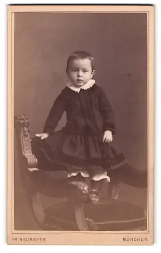 Fotografie Fr. Neumayer, München, Neuhauserstrasse 29, Kleinkind im Kleidchen, auf einem Stuhl stehend