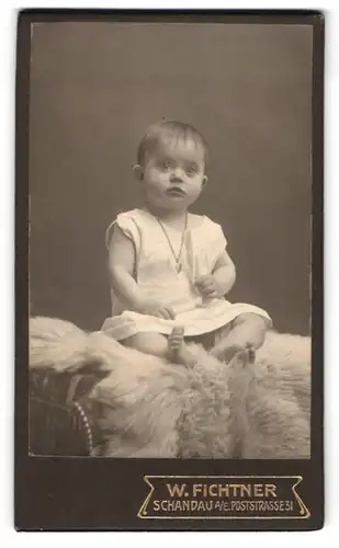 Fotografie W. Fichtner, Schandau a. E., Poststr. 31, Kleinkind im Hemd sitzt auf einem Fell