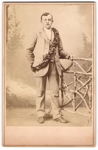 Fotografie unbekannter Fotograf und Ort, Junger Herr mit einem Kranz um den Körper