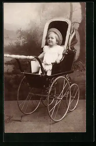 Foto-AK Kleines Kind im Kinderwagen vor einer Kulisse