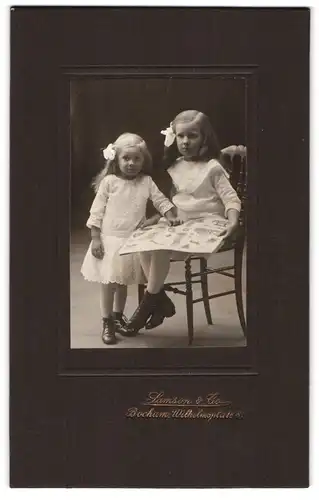 Fotografie Samson & Co., Bochum, Wilhelmsplatz 8, Zwei kleine Mädchen mit Haarschleifen in weissen Kleidchen