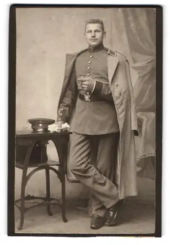 Fotografie unbekannter Fotograf und Ort, Uniformierter Soldat mit Mantel und Schirmmütze