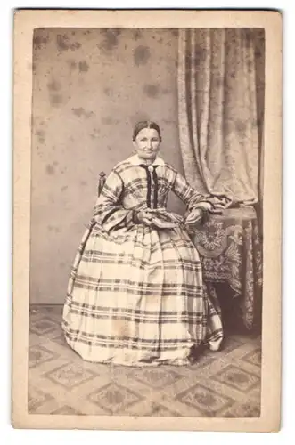 Fotografie unbekannter Fotograf und Ort, Dame im karierten Kleid mit Brosche und Fotoalbum auf dem Schoss
