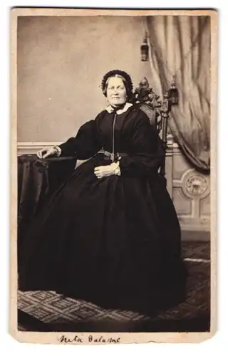 Fotografie unbekannter Fotograf und Ort, Portrait ältere Dame im tief schwarzen Kleid mit Haube sitzend im Atelier