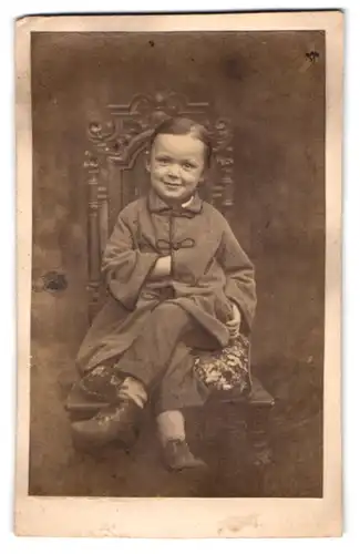 Fotografie unbekannter Fotograf und Ort, Portrait junger Knabe mit überschalgenen Beinen posiert im Atelier