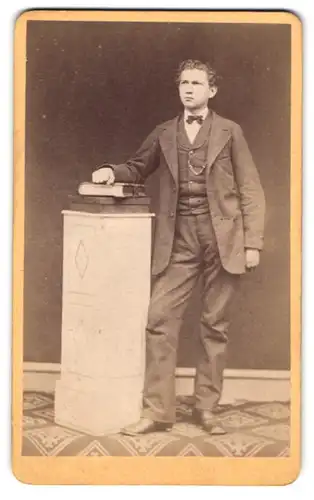 Fotografie Friedrich Rinck, Kandel, junger Mann im Anzug mit Fliege posiert stehend im Atelier